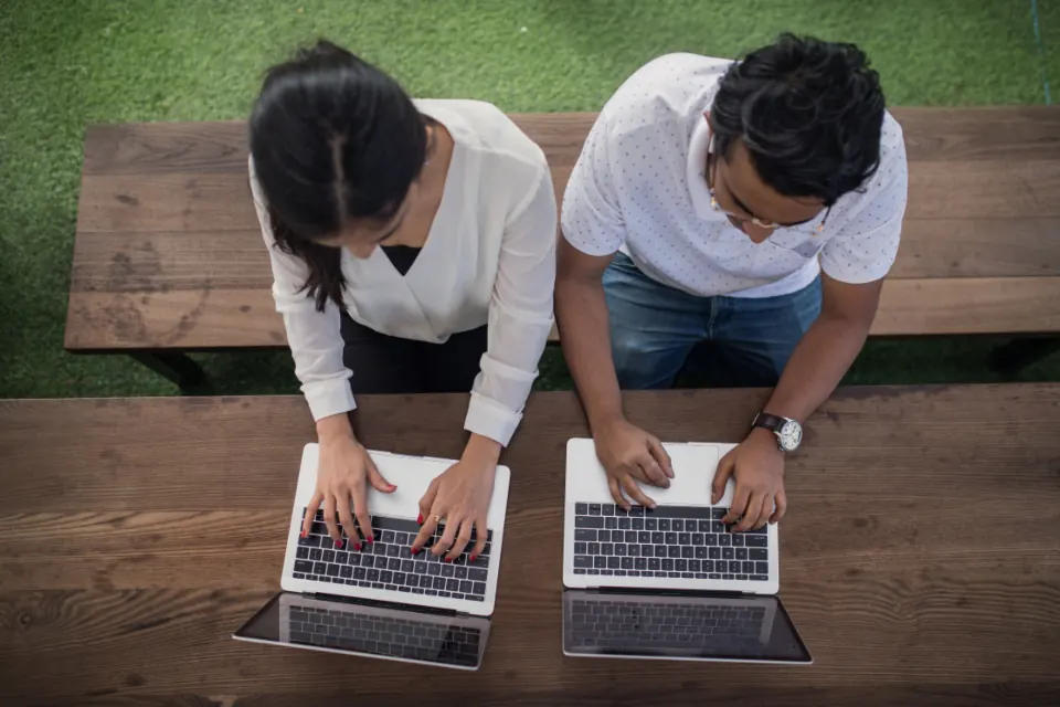 Two colleagues working side by side on laptops