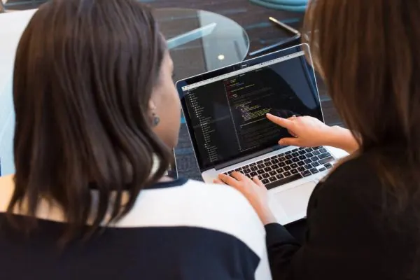 Two women reviewing code together on a laptop