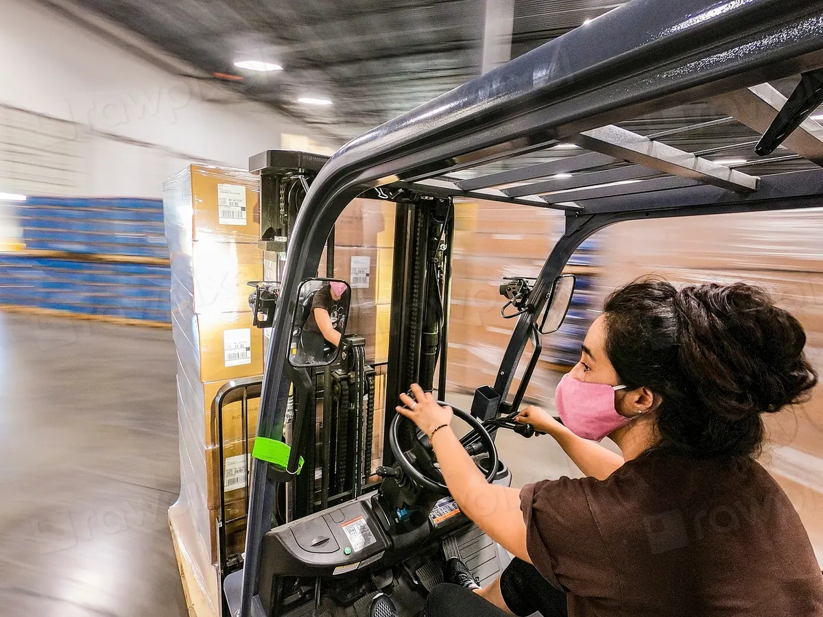 Woman driving a forklift between warehouse racks