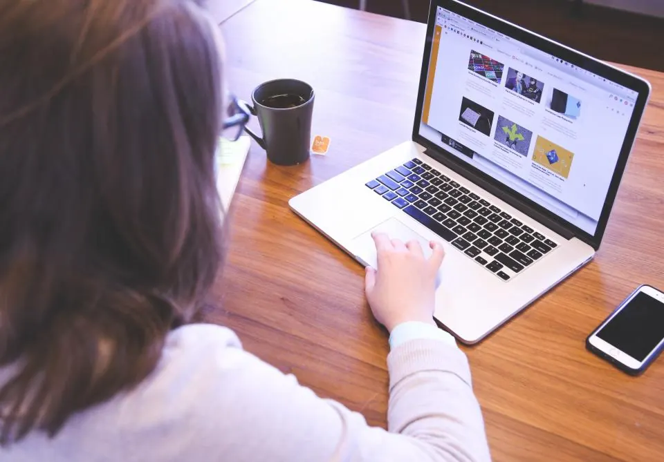 Woman working on a laptop at a wooden desk