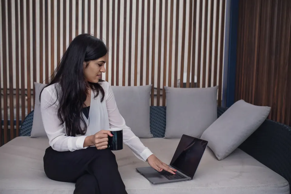 Woman working on a laptop while sitting on a sofa